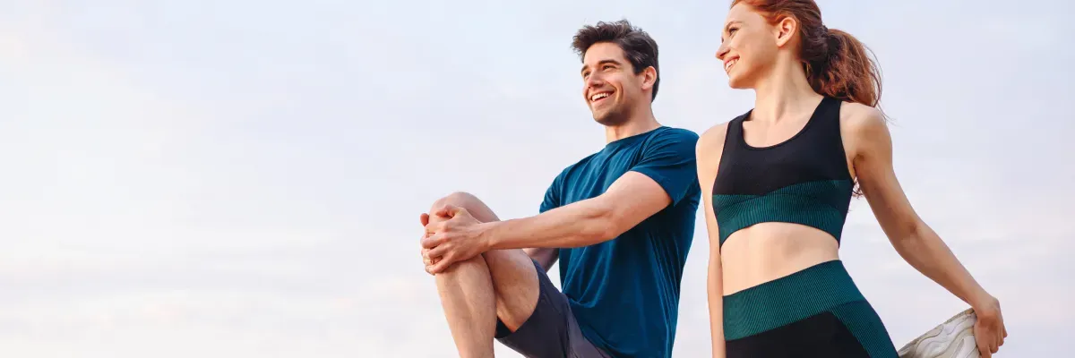Man and woman stretching outdoors; Mattress Direct highlights how quality sleep supports active muscle recovery.